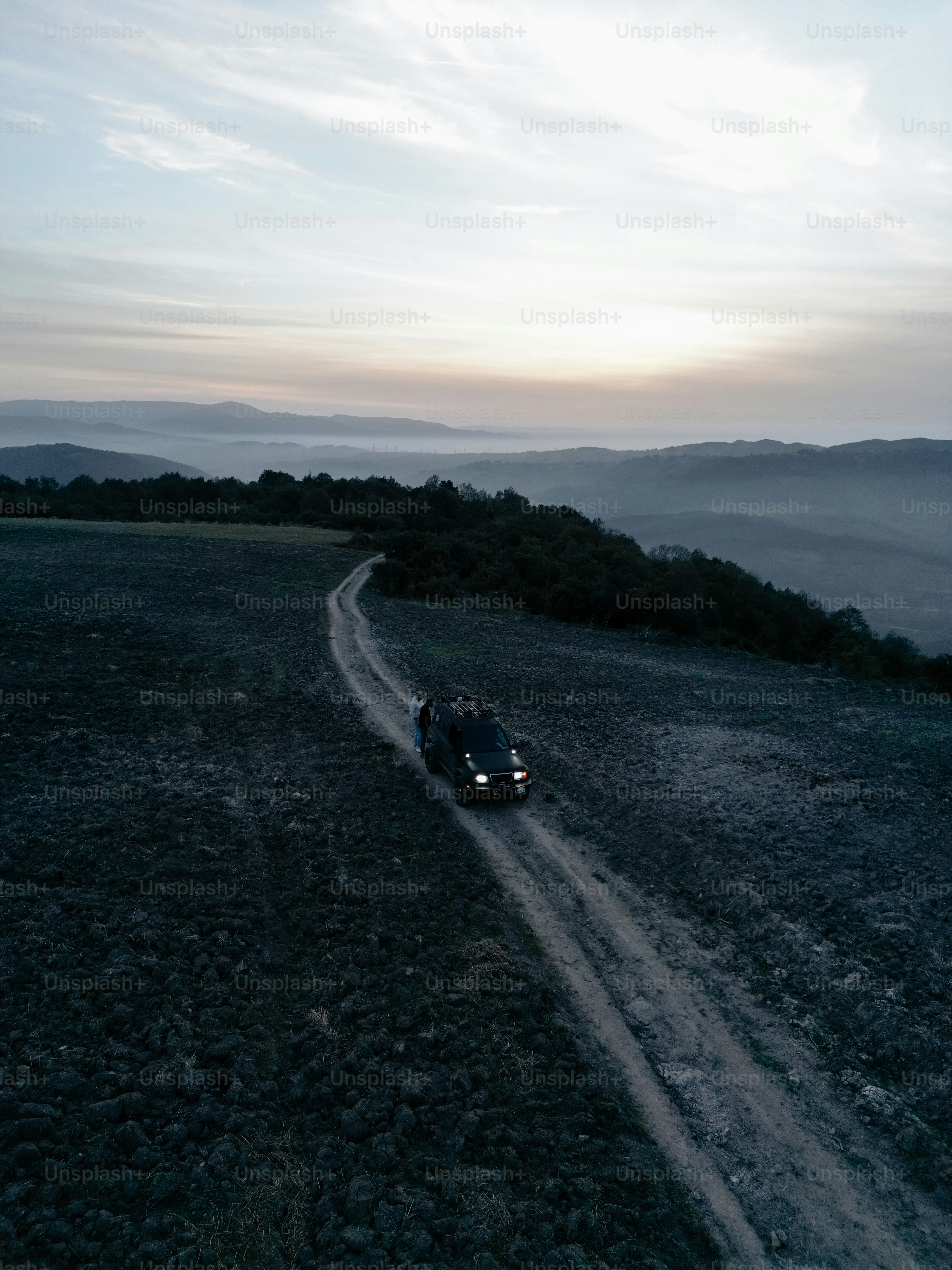 a car driving down a dirt road in the middle of a field