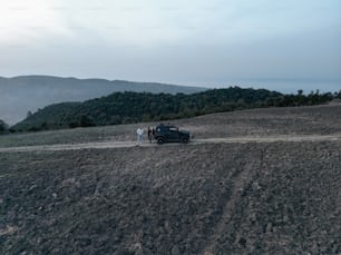 duas pessoas ao lado de um carro em uma estrada de terra
