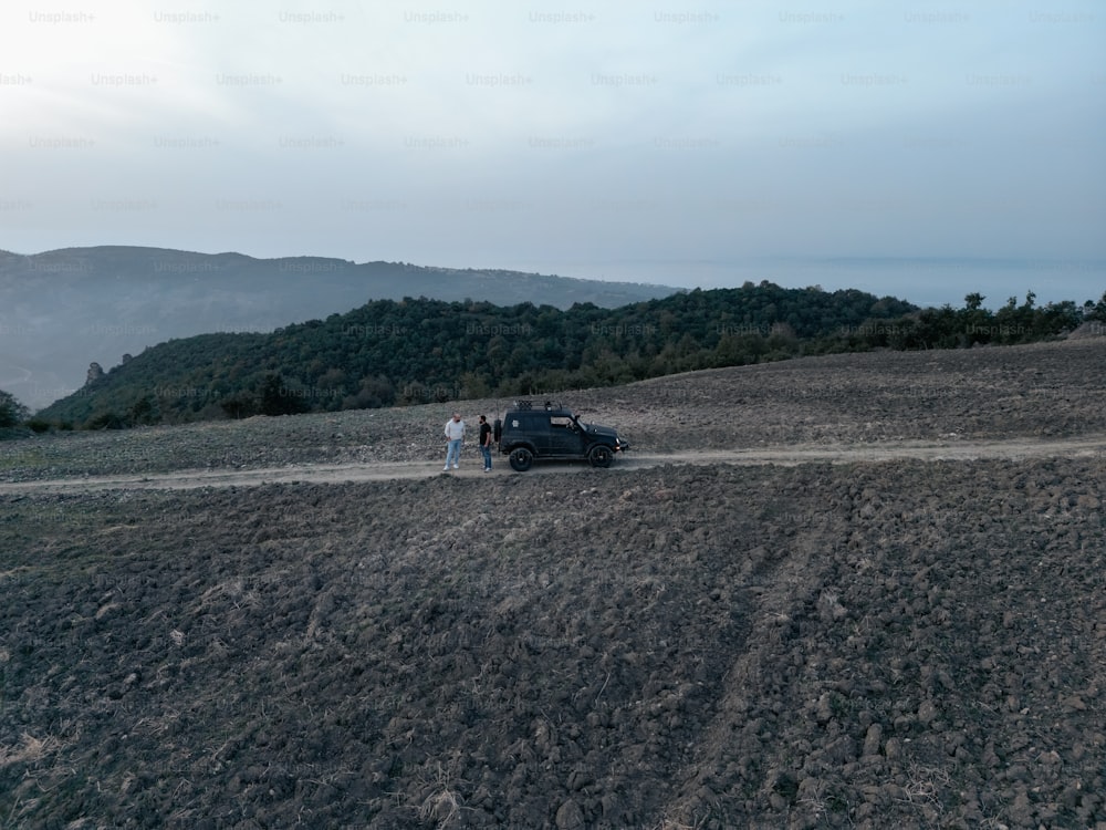 Dos personas de pie junto a un coche en un camino de tierra