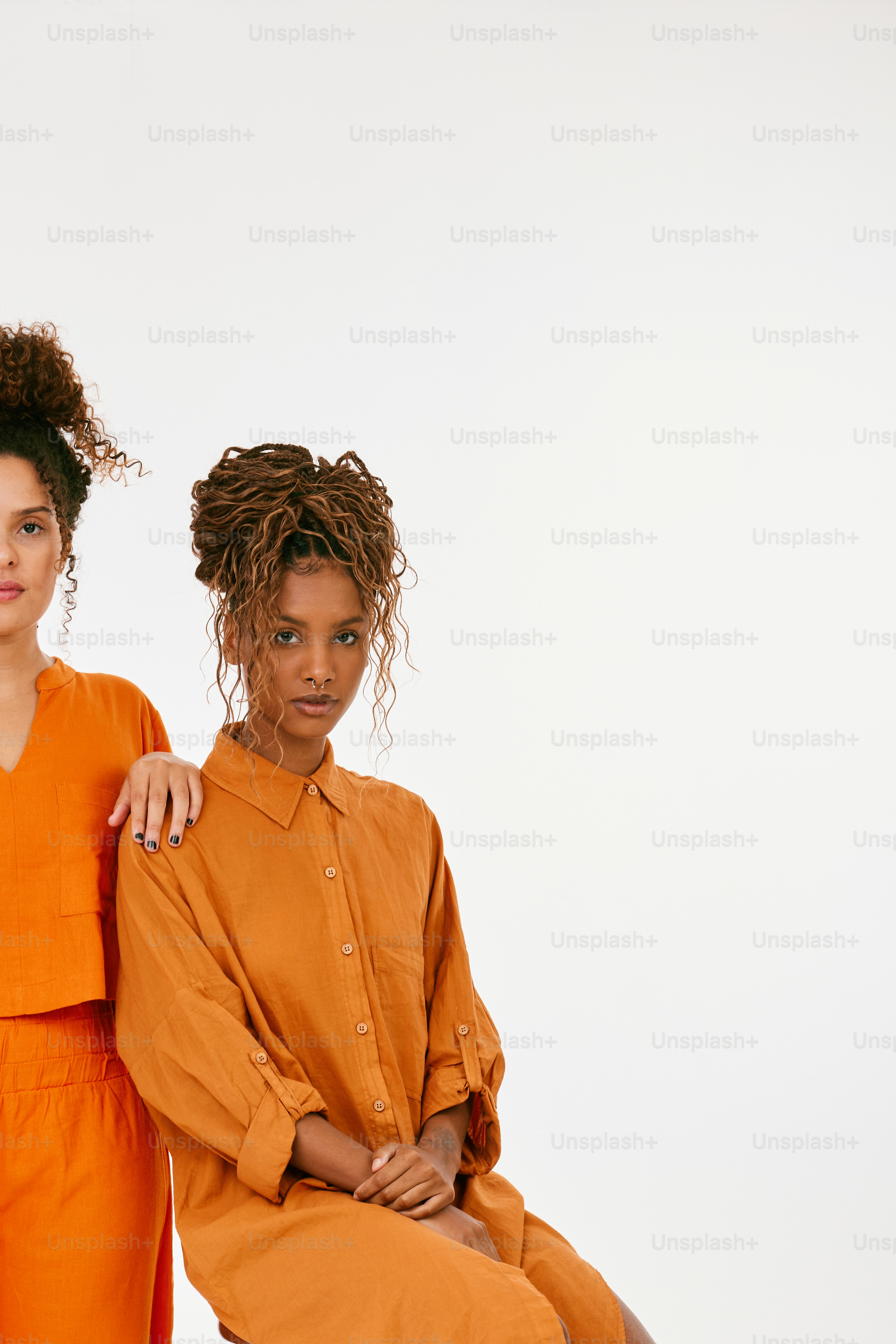 two women in orange outfits sitting next to each other