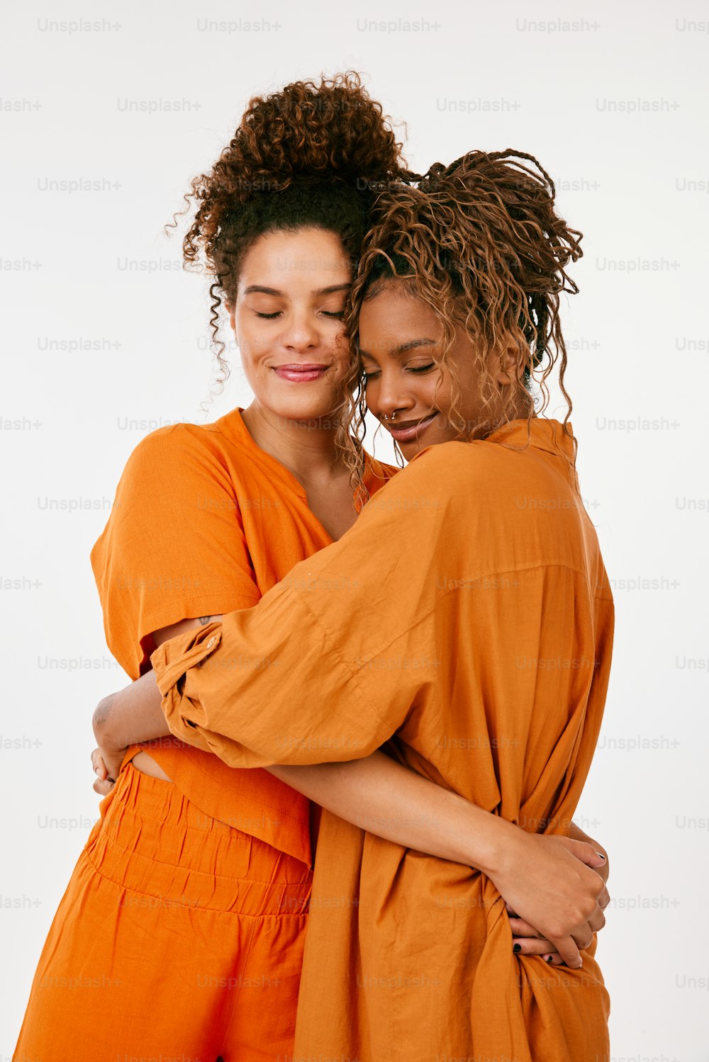 two women hugging each other in orange outfits