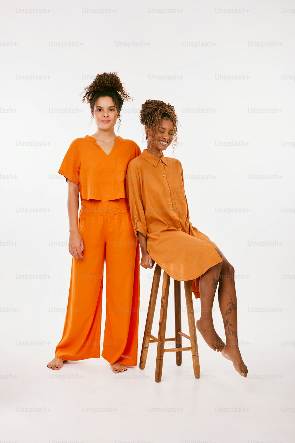 two women sitting on stools posing for a picture