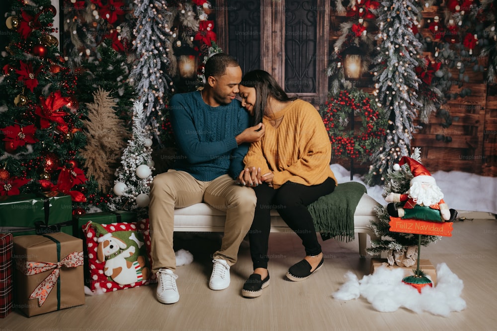 a man and woman sitting on a bench in front of a christmas tree