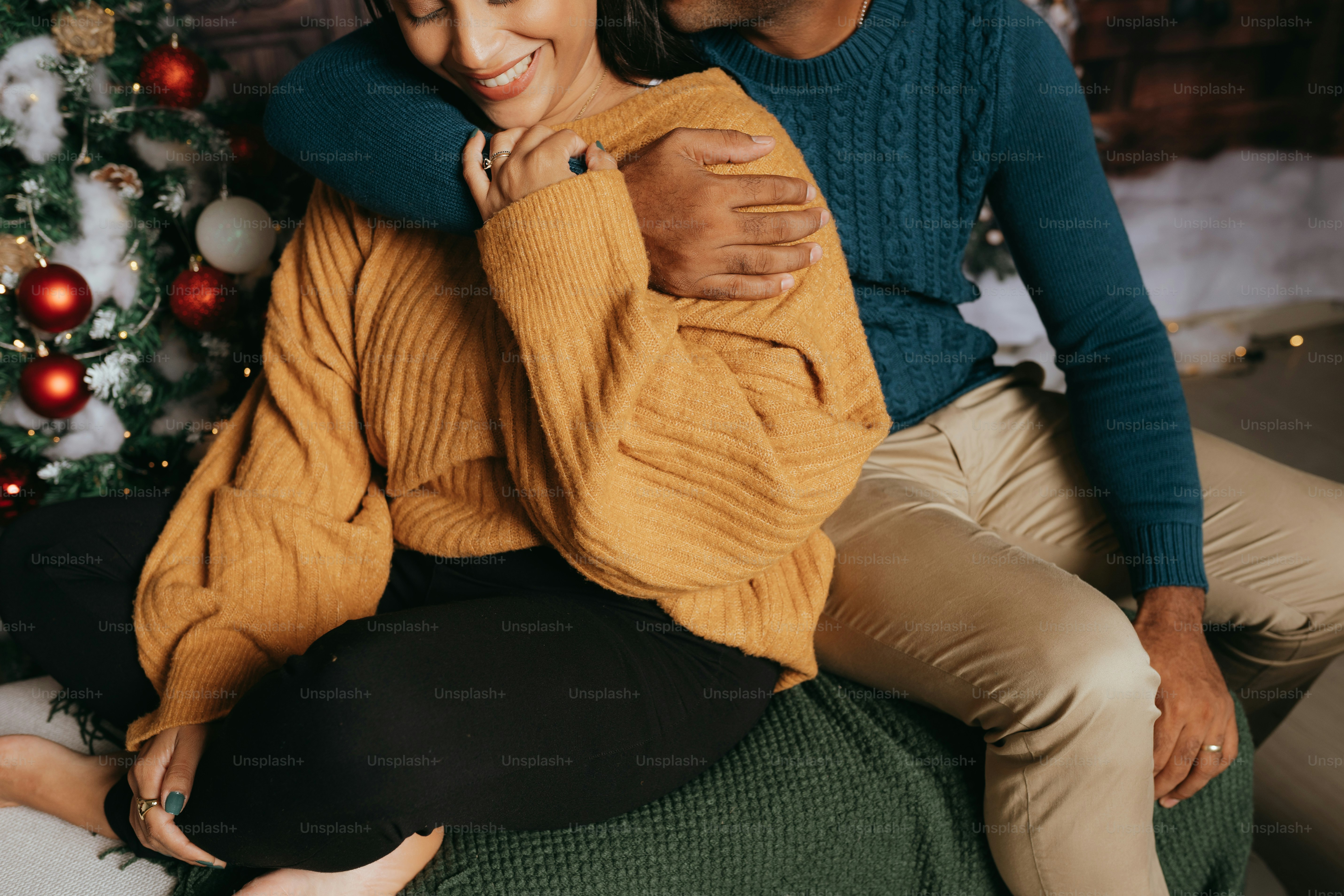 a man and a woman sitting next to a christmas tree