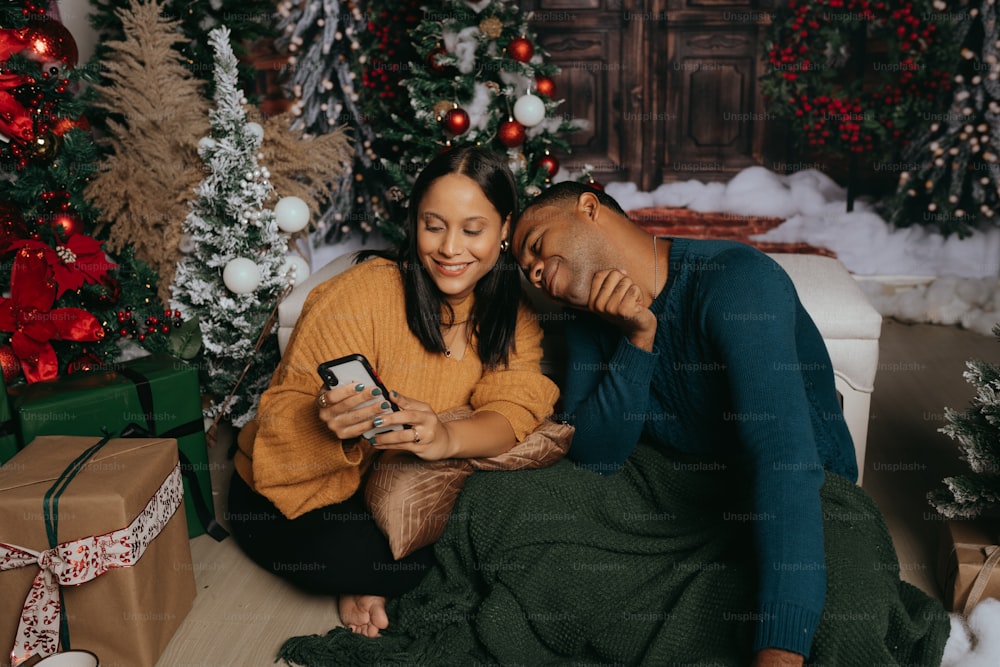 a man and woman sitting next to each other in front of christmas trees