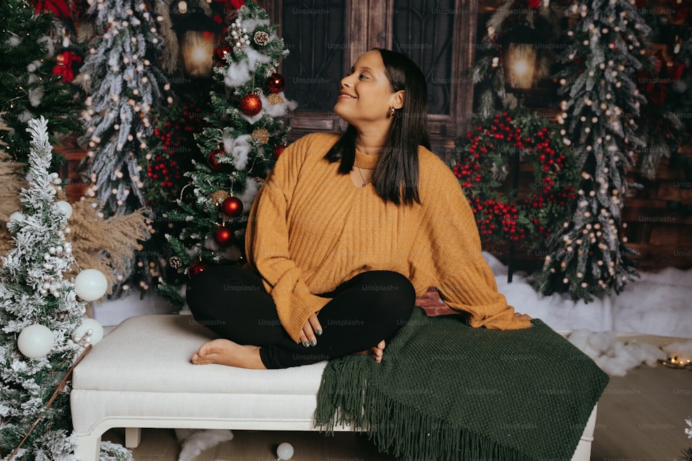 a woman sitting on a bench in front of a christmas tree