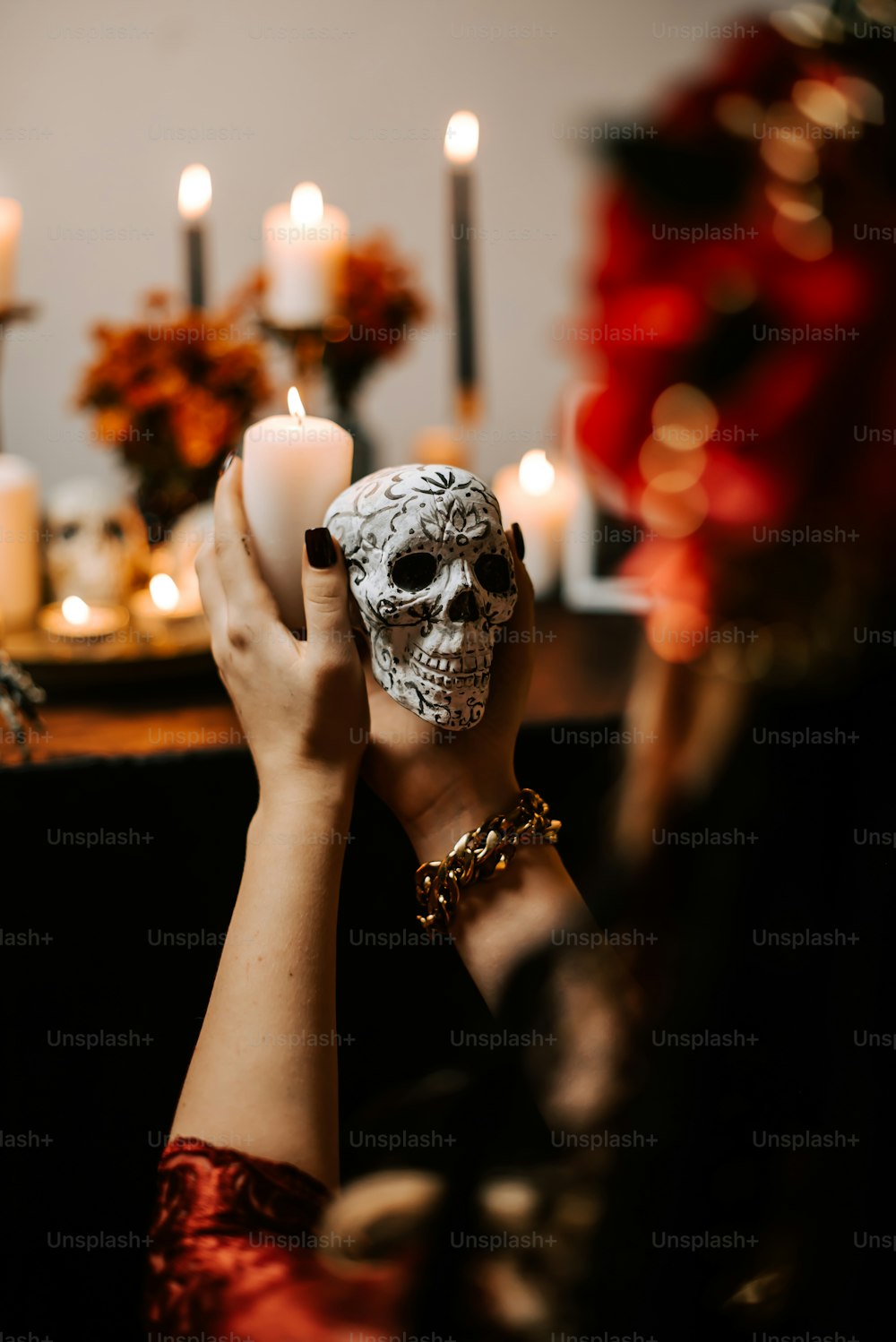 a woman holding a skull in front of a table with candles