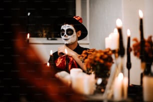 a young boy with a skeleton face paint sitting in front of candles