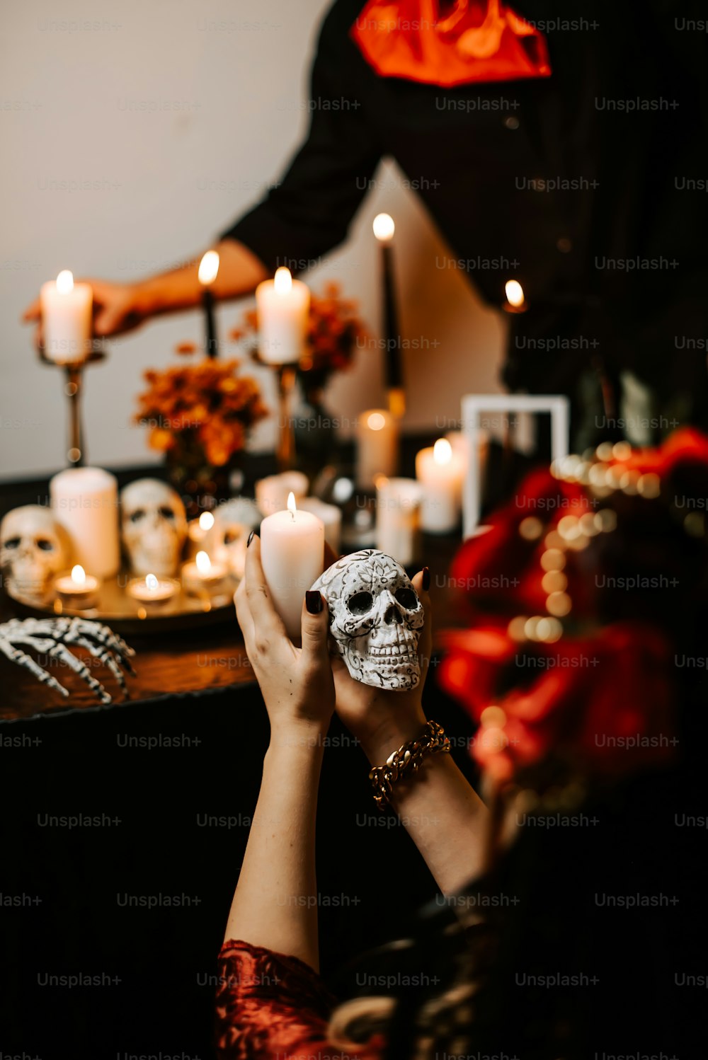 a person holding a skull in front of a table with candles