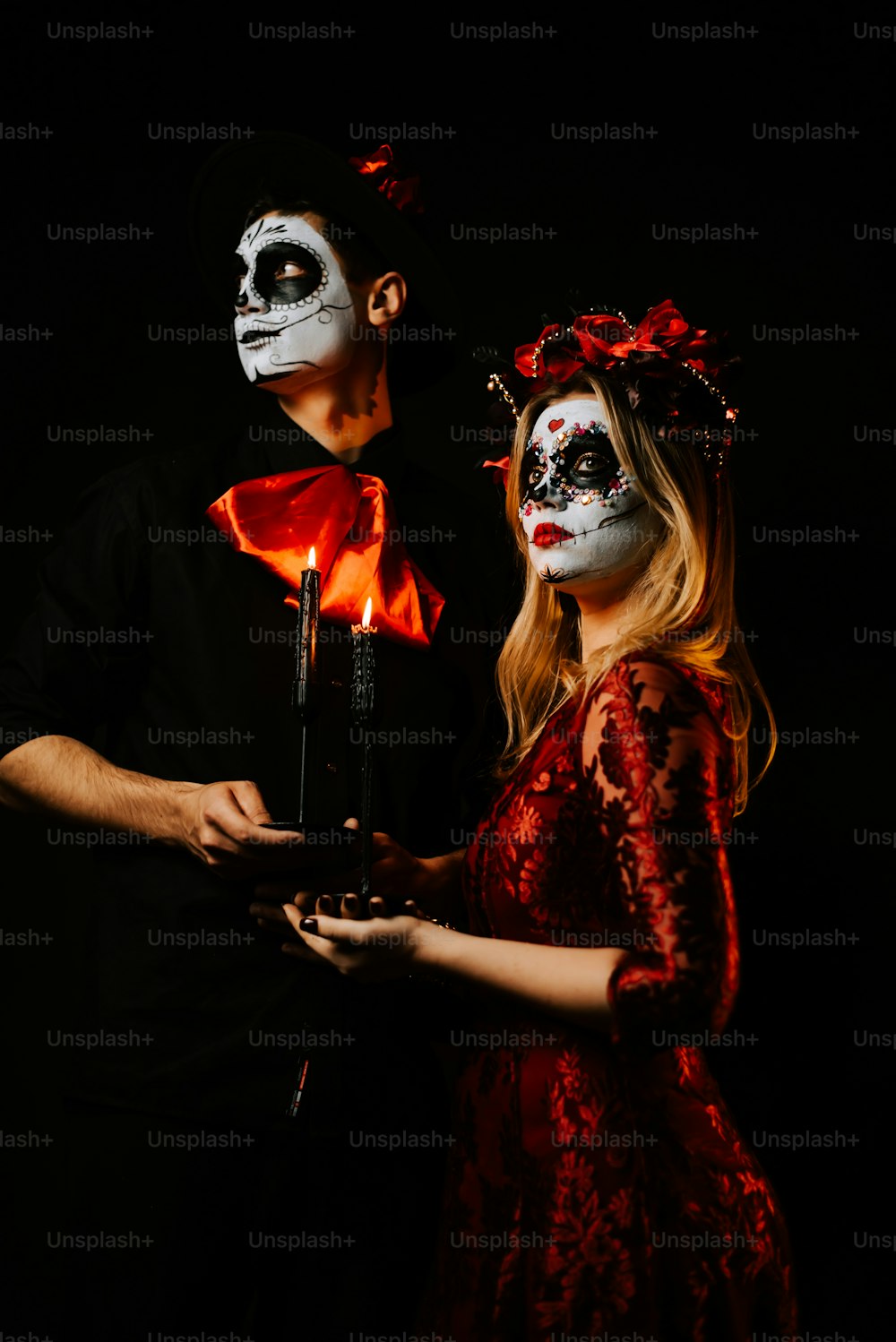 a man and a woman in skeleton makeup holding a lit candle