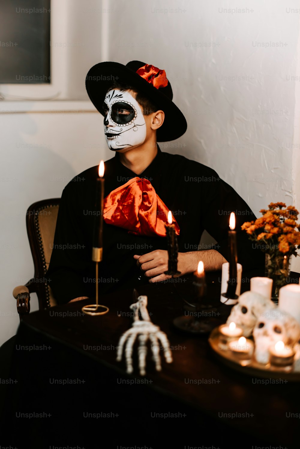 a man in a skeleton mask sitting at a table with candles