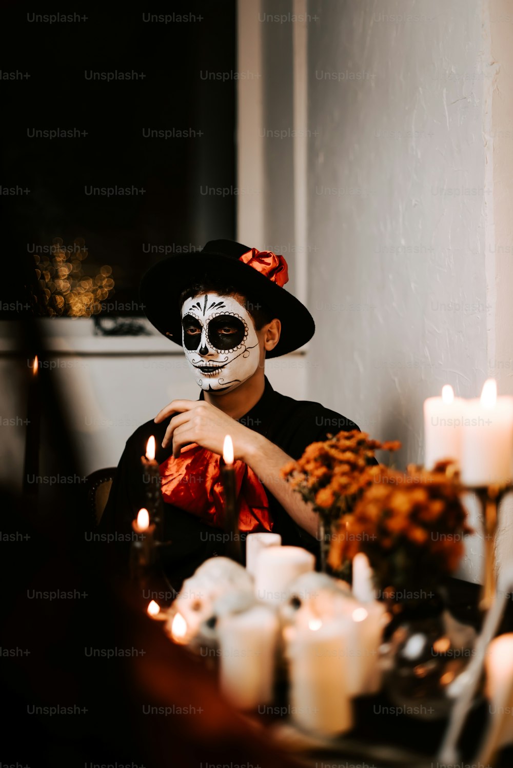 a man in a skeleton mask sitting at a table with candles