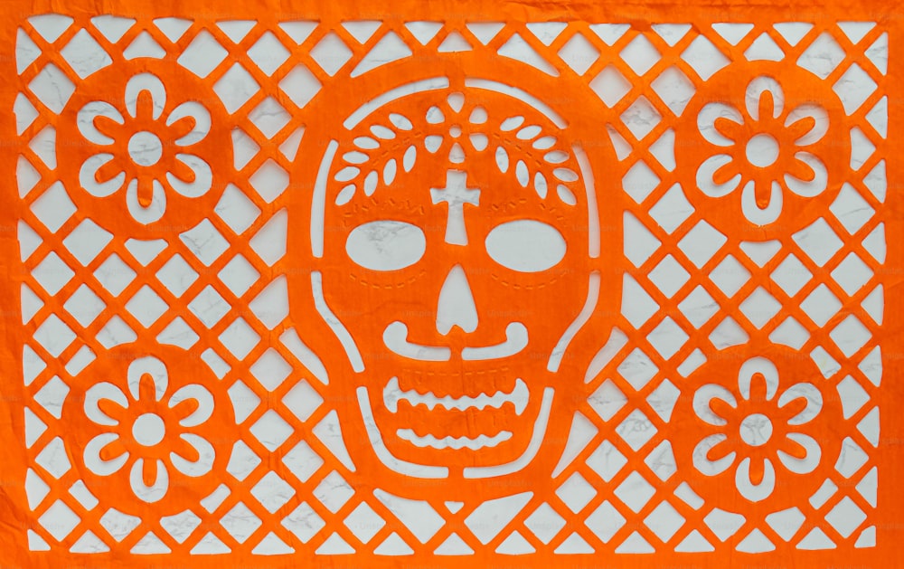 ein orangefarbener Scherenschnitt eines Totenschädels auf weißem Hintergrund