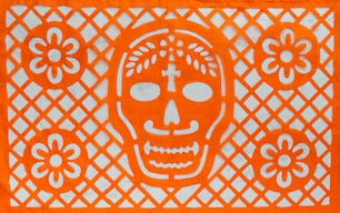 an orange paper cutout of a skull on a white background