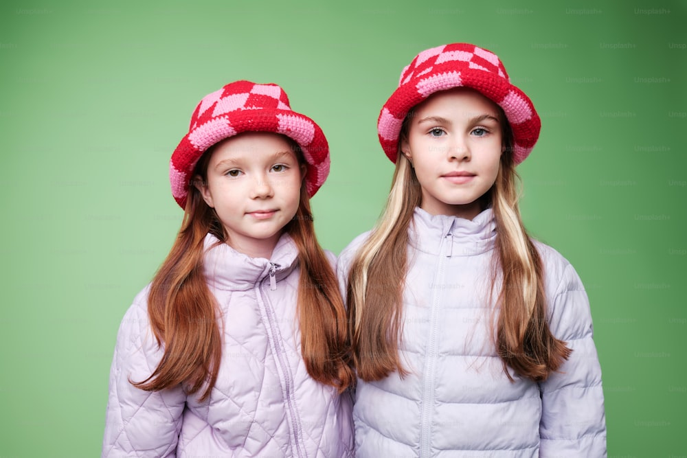 two young girls wearing red and white hats