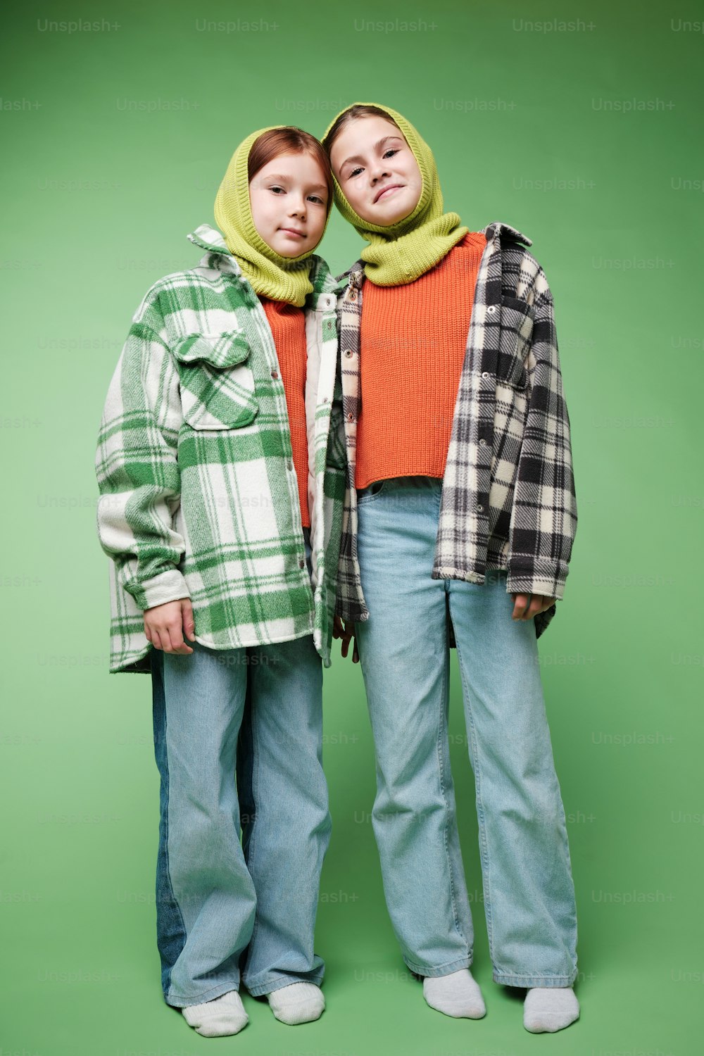 two people standing next to each other in front of a green background