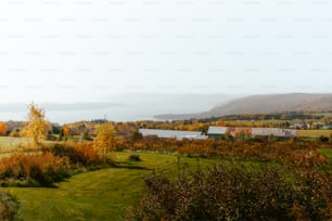 a field with a house and a lake in the background