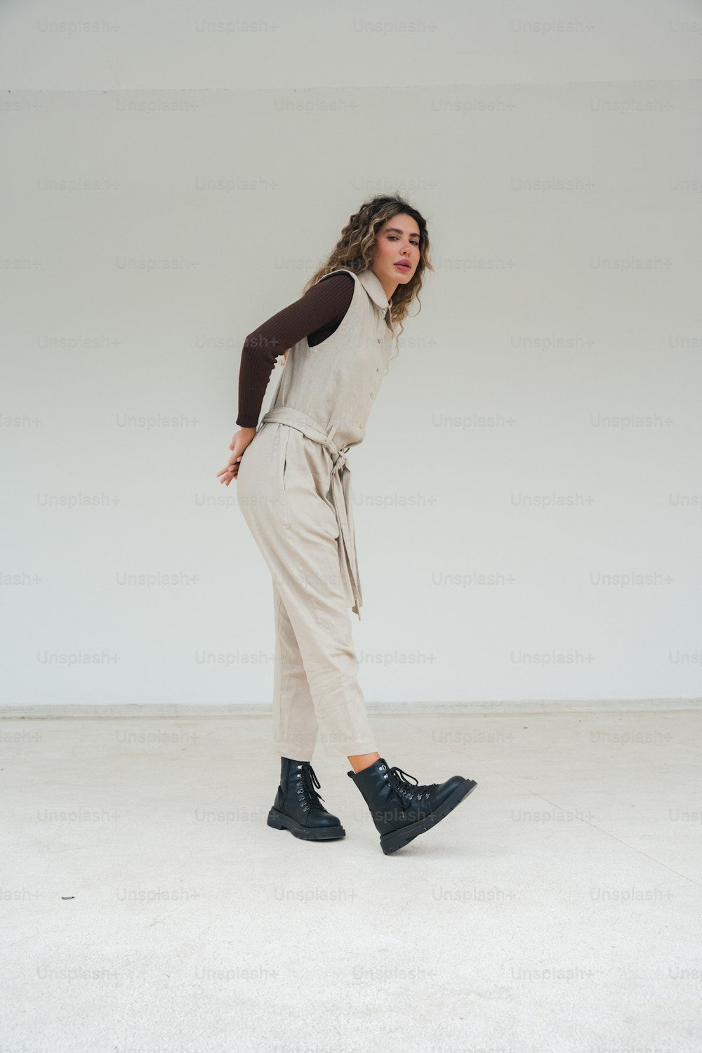 a woman in a white jumpsuit and black boots