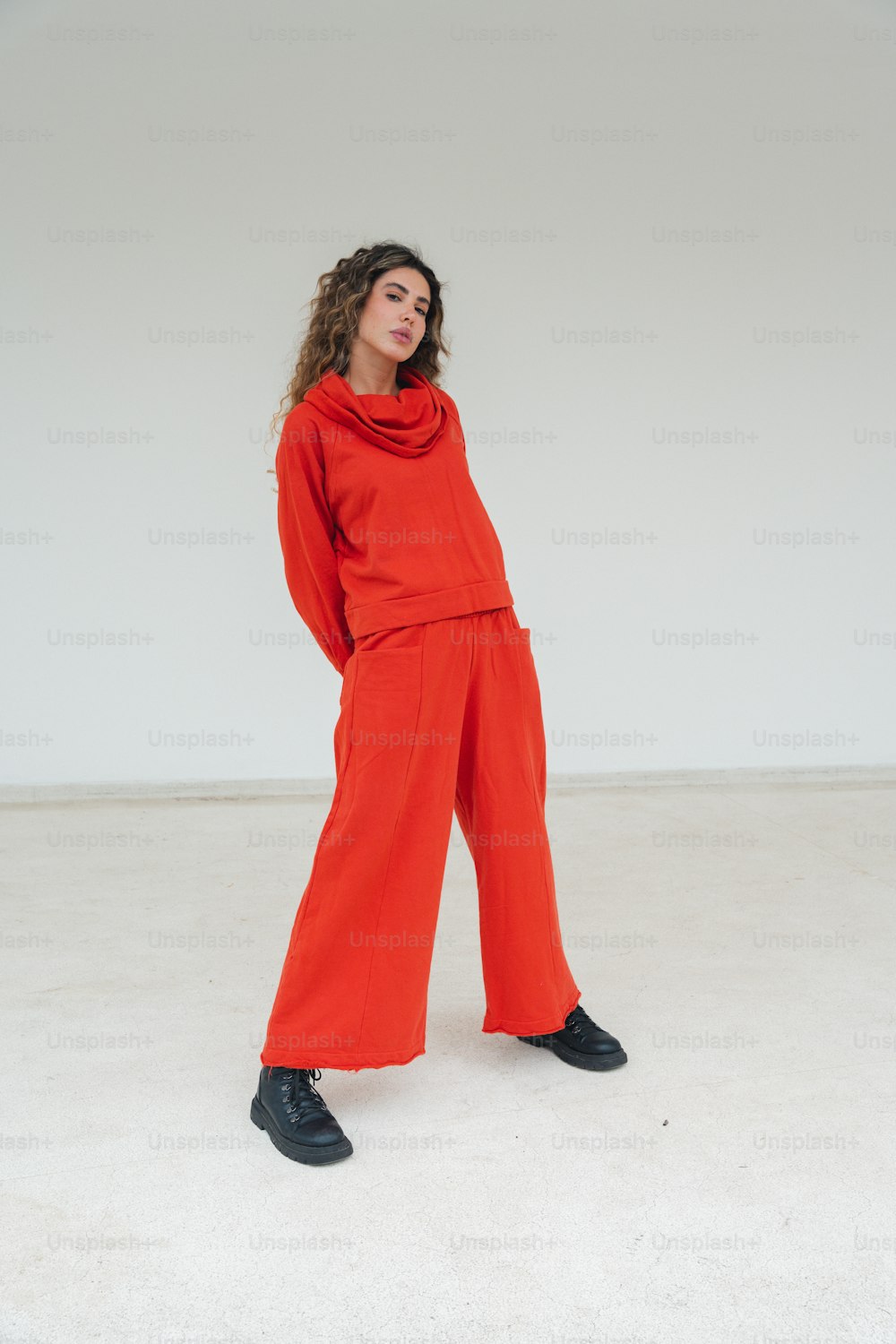 a woman wearing a red sweater and wide legged pants