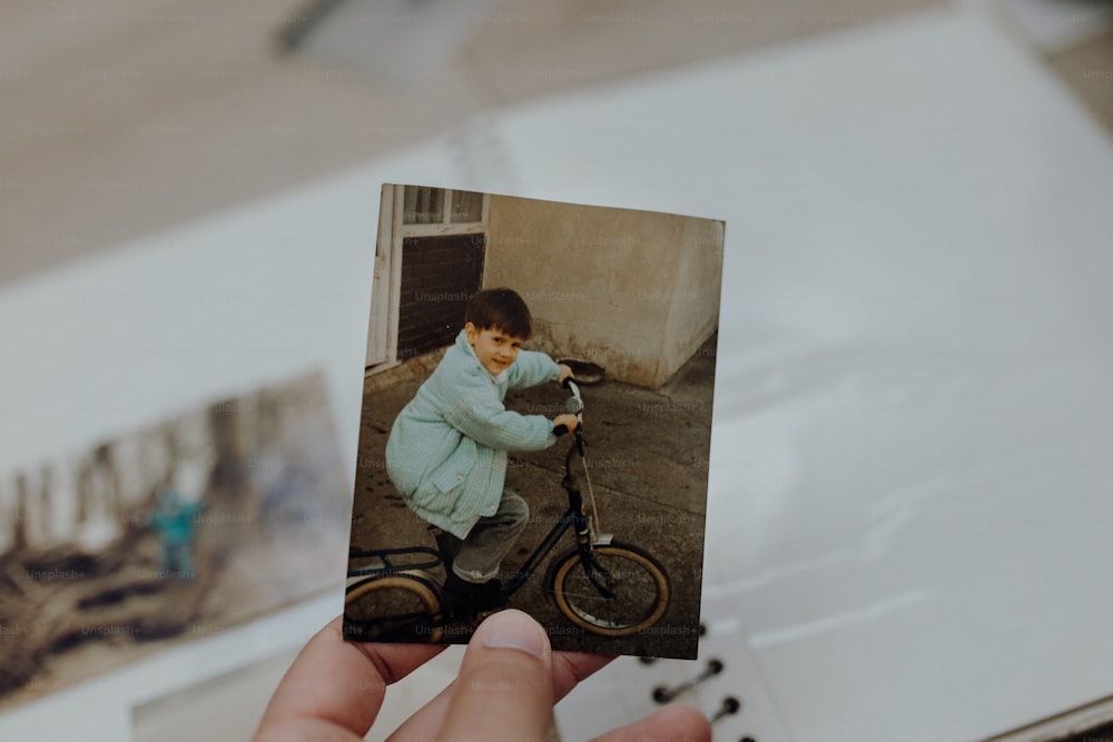 a person holding a photo of a boy on a bike