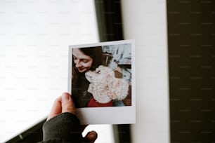 a person holding up a polaroid picture of a dog