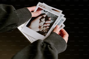 uma pessoa segurando um monte de fotos em suas mãos