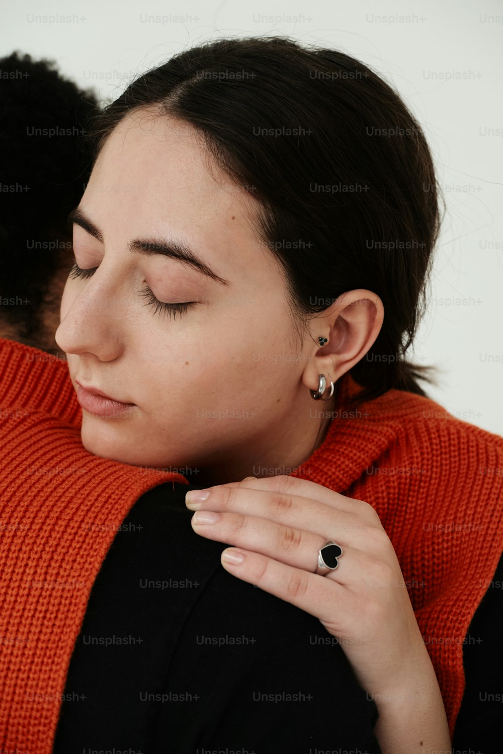a woman with her eyes closed wearing a red sweater