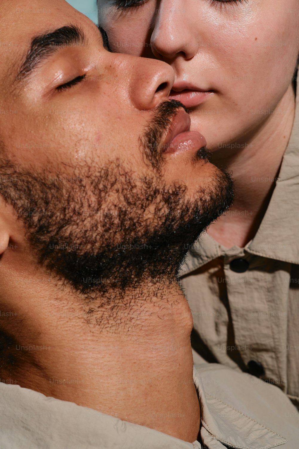 a man kissing another man's cheek with his eyes closed