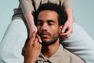 a man sitting on a woman's back with his hands on his head