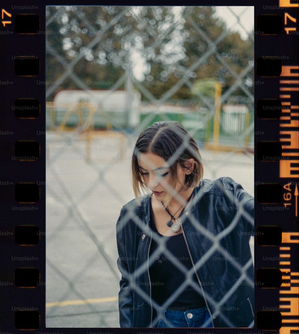 a woman standing behind a chain link fence