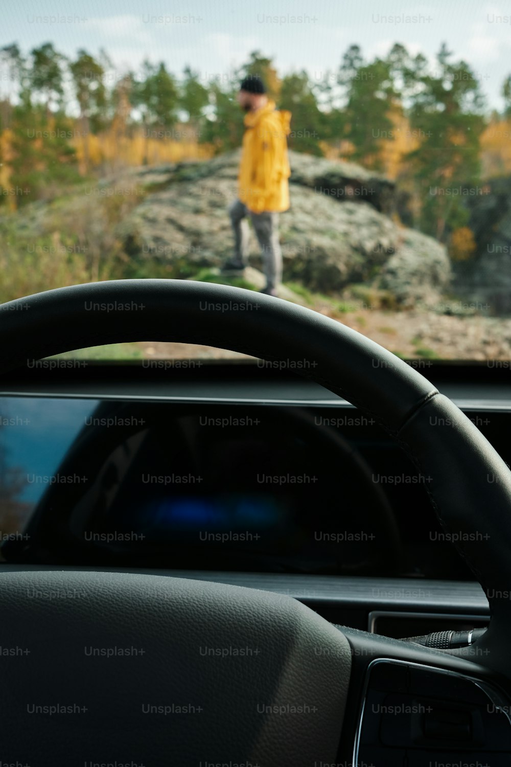 a man in a yellow jacket is driving a car