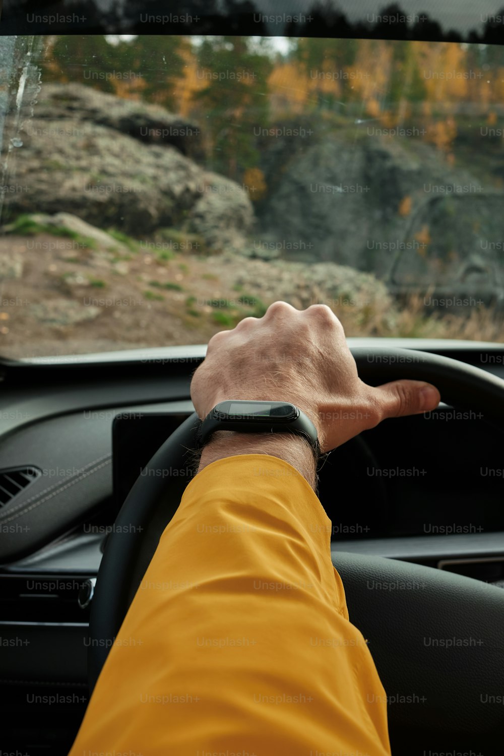 a man driving a car with his hand on the steering wheel