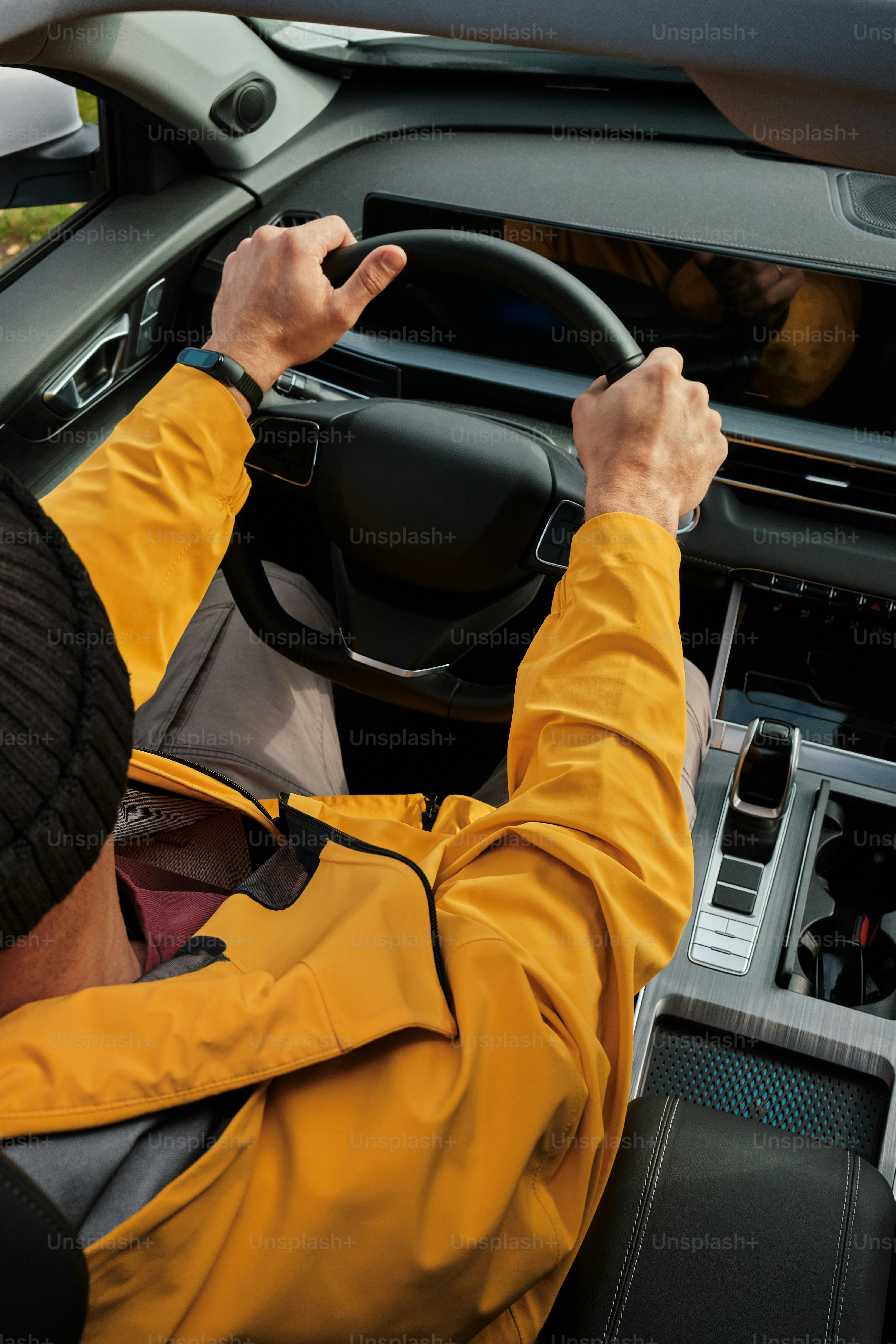 a man in a yellow jacket driving a car