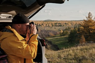 a man in a yellow jacket taking a picture of a field