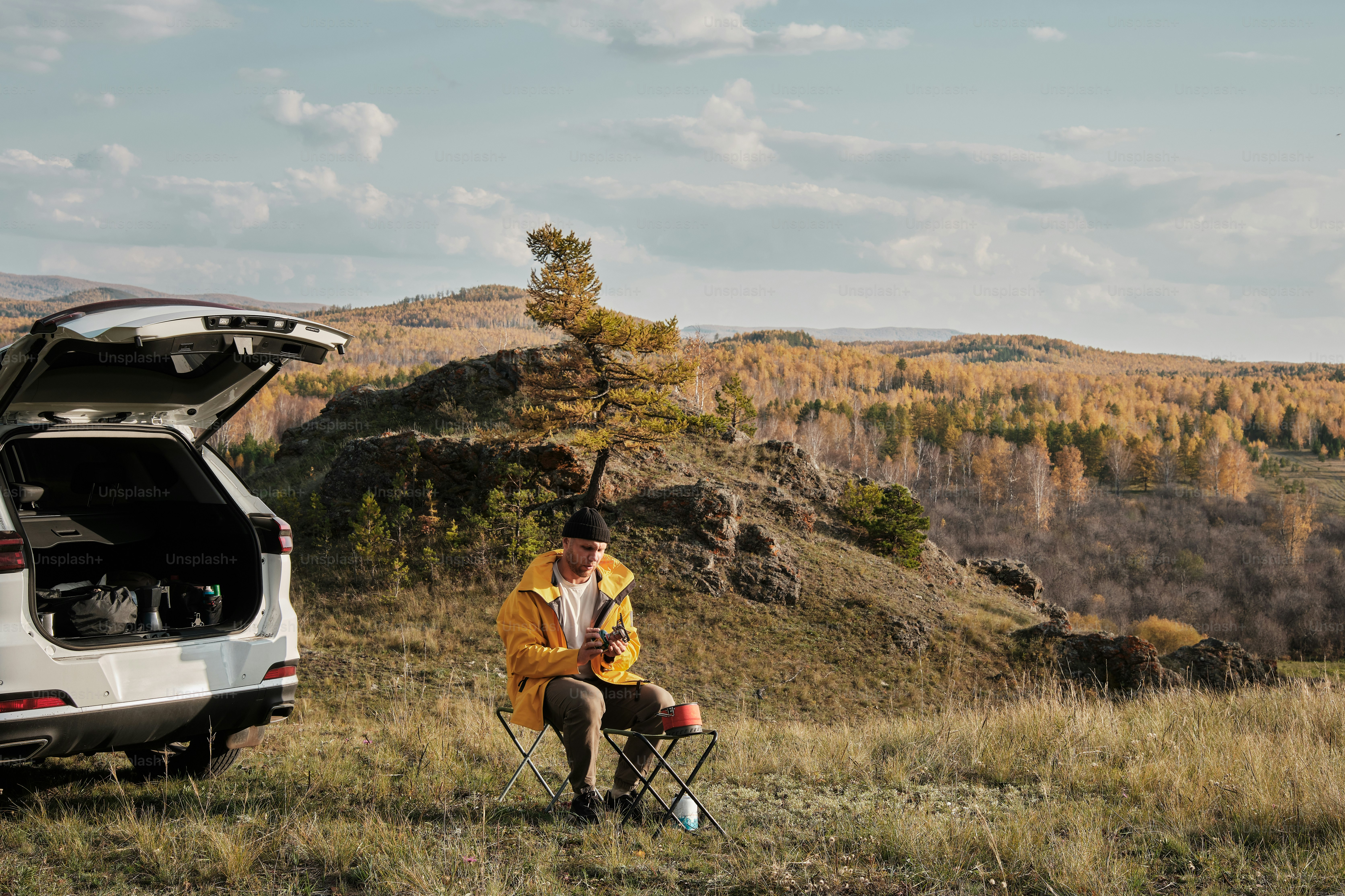 um homem sentado em uma cadeira ao lado de um carro