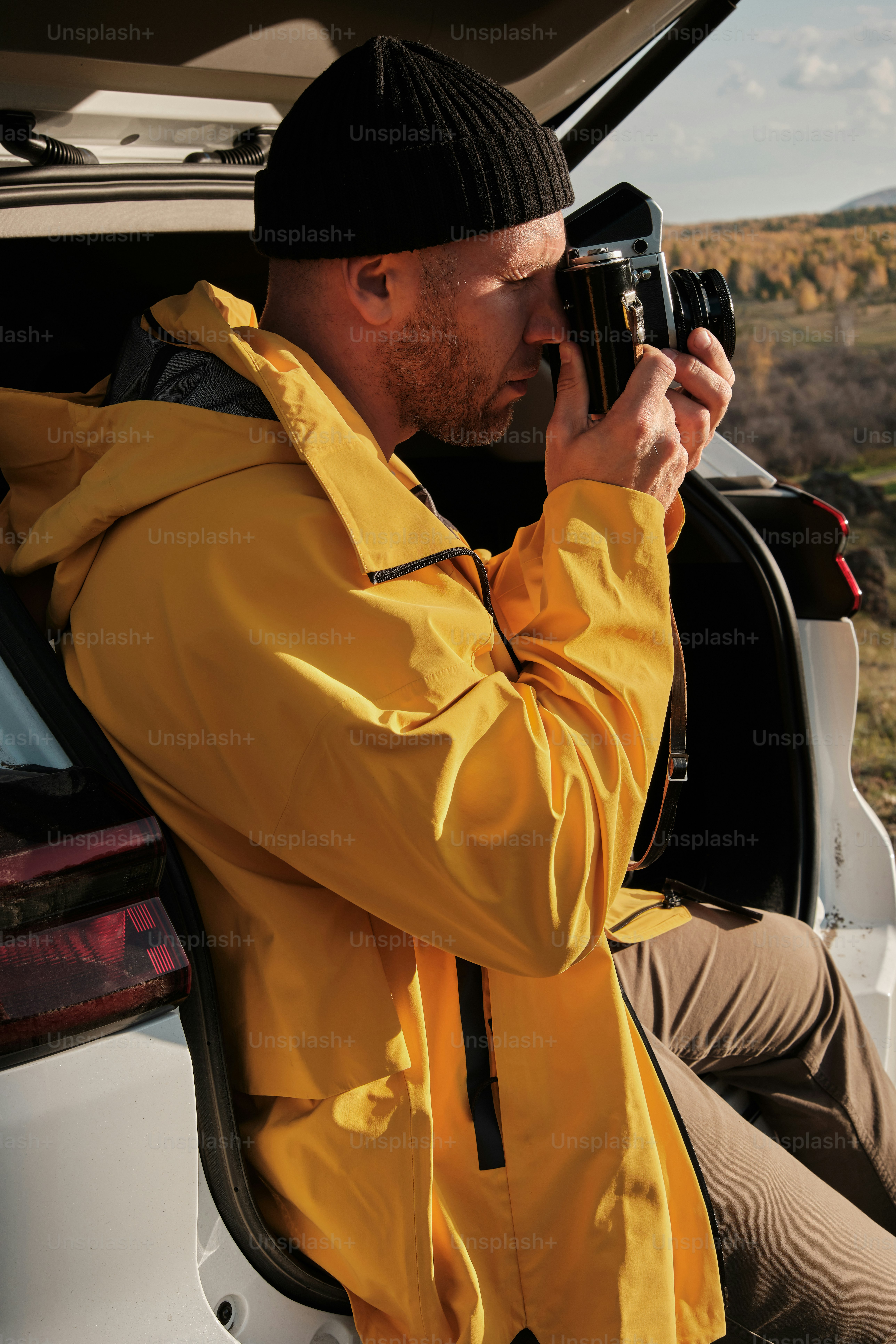 Un homme assis à l’arrière d’une voiture tenant un appareil photo