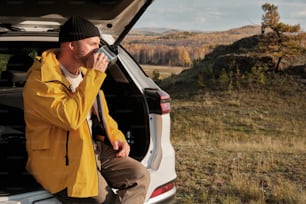 a man sitting in the back of a car drinking from a cup