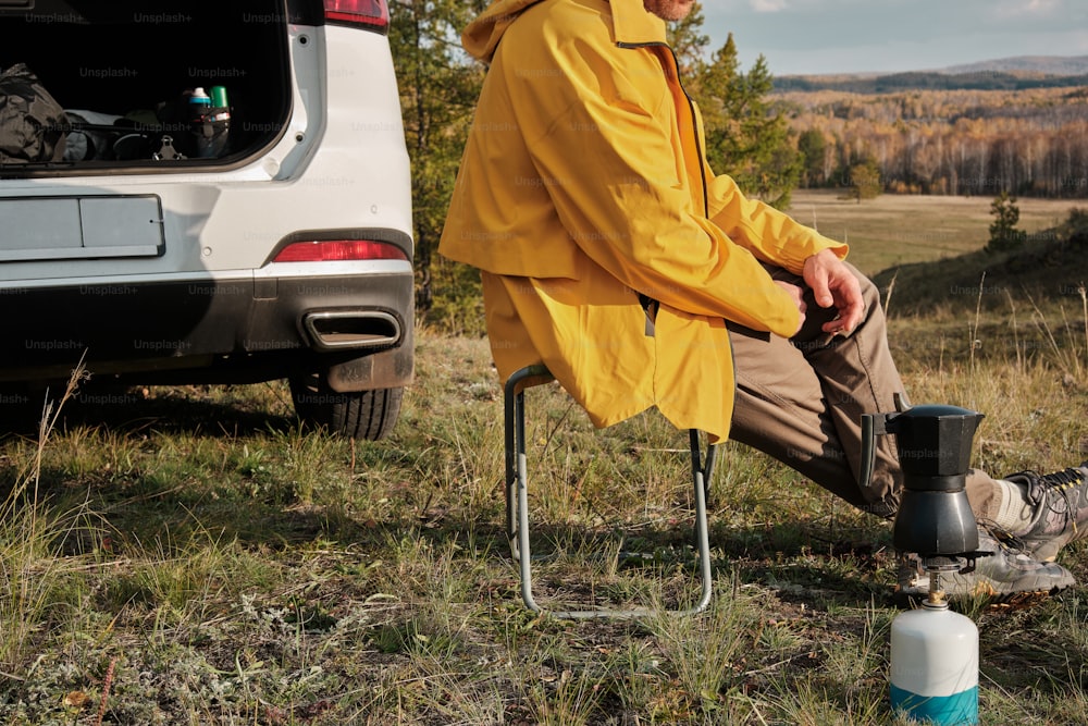 a man sitting on a chair next to a car