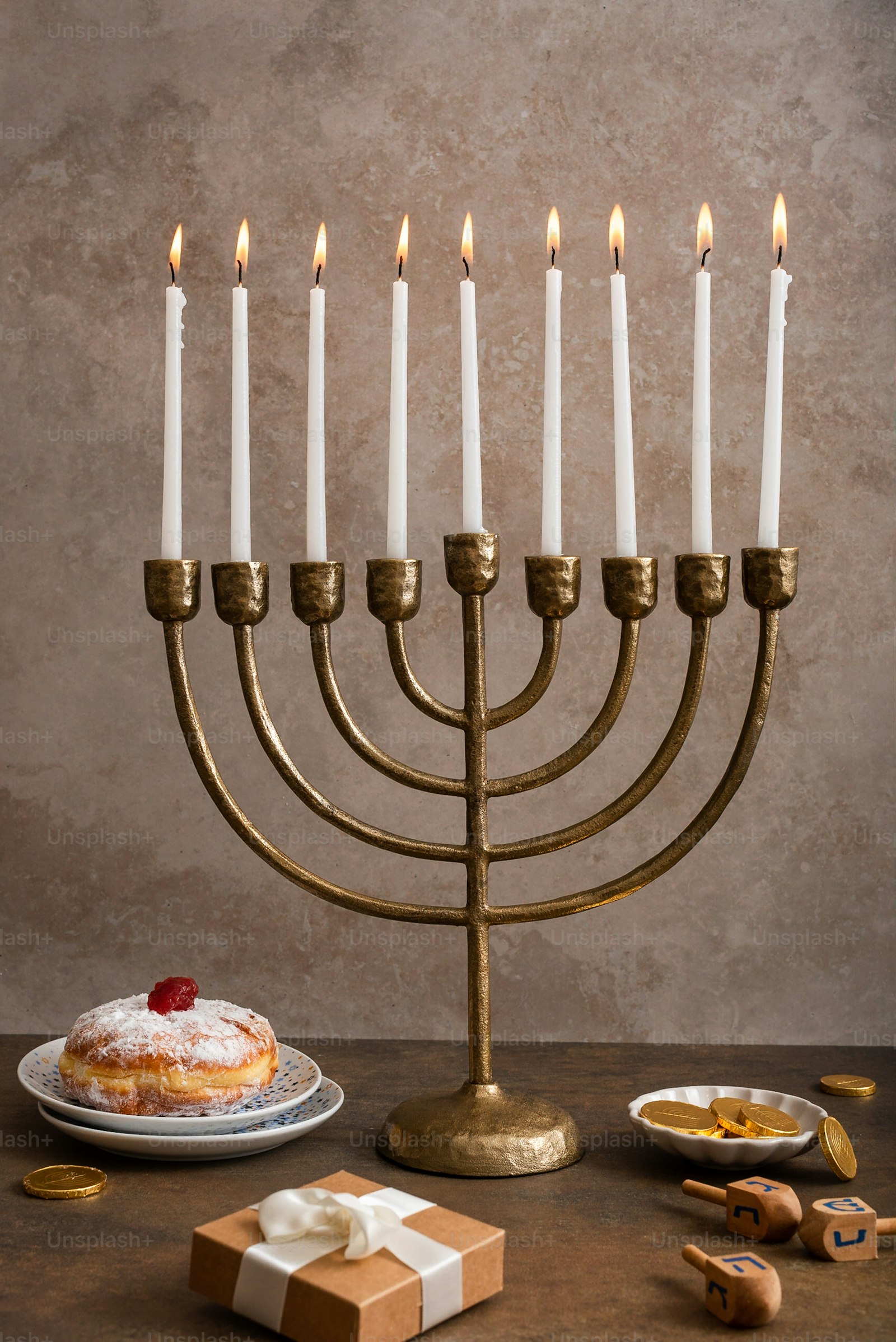 Hanukkah menorah with lit candles, sufganiyot, and gifts