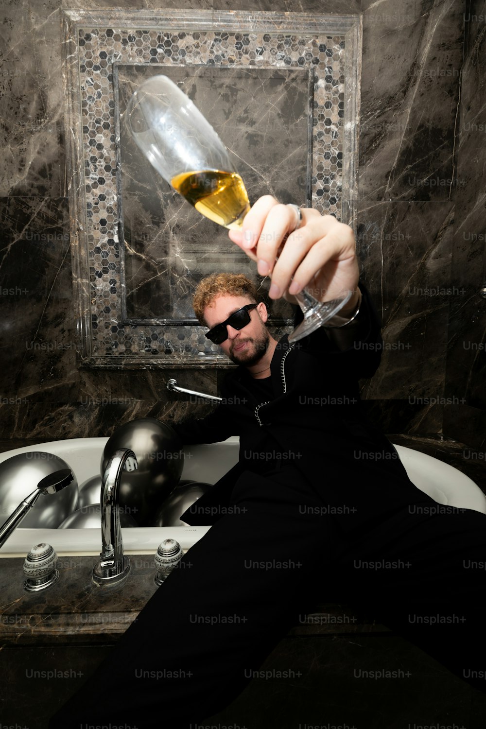 a man holding a wine glass in front of a sink