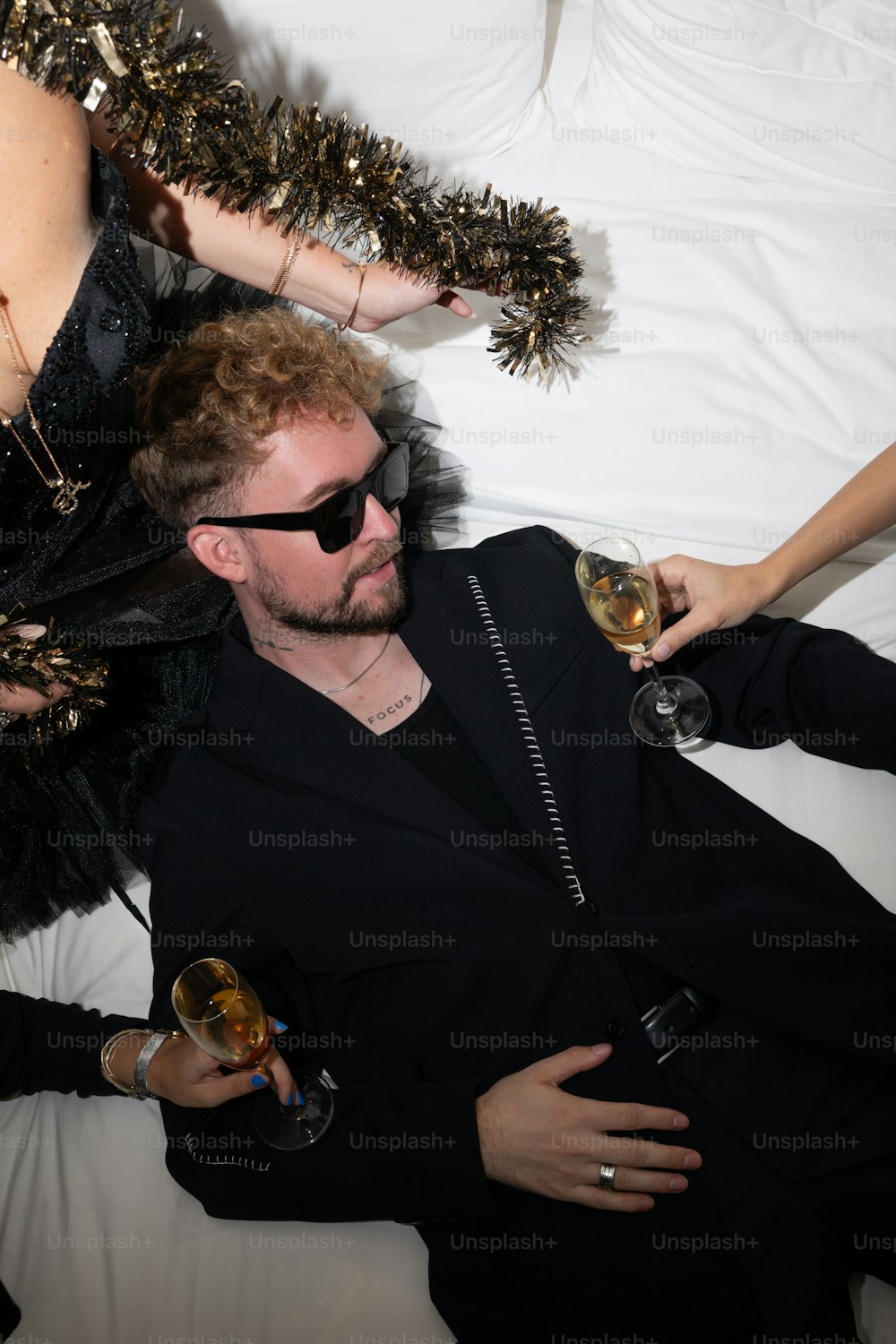 a man laying on a bed with two women holding wine glasses