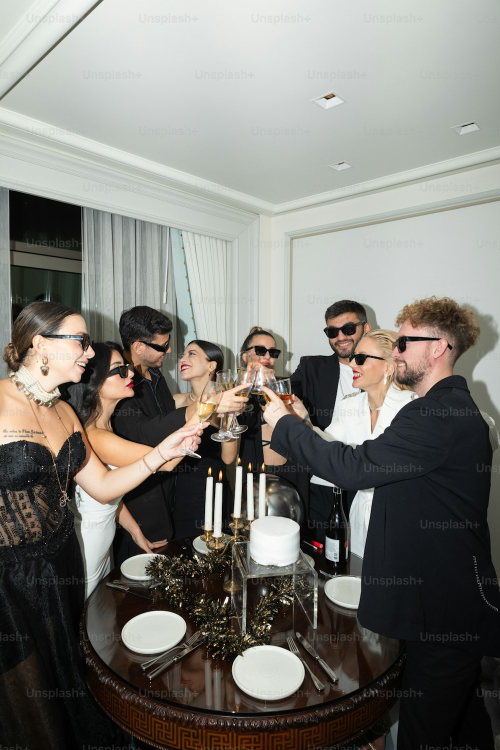 un gruppo di persone in piedi intorno a un tavolo con in mano bicchieri di vino