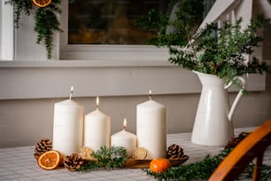 uma mesa coberta com velas brancas ao lado de uma janela