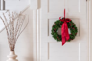 a wreath hanging on a door with a red bow