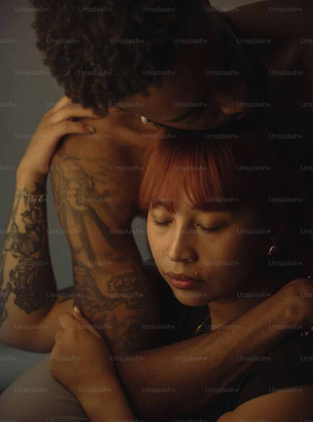 a woman with red hair hugging a man with tattoos