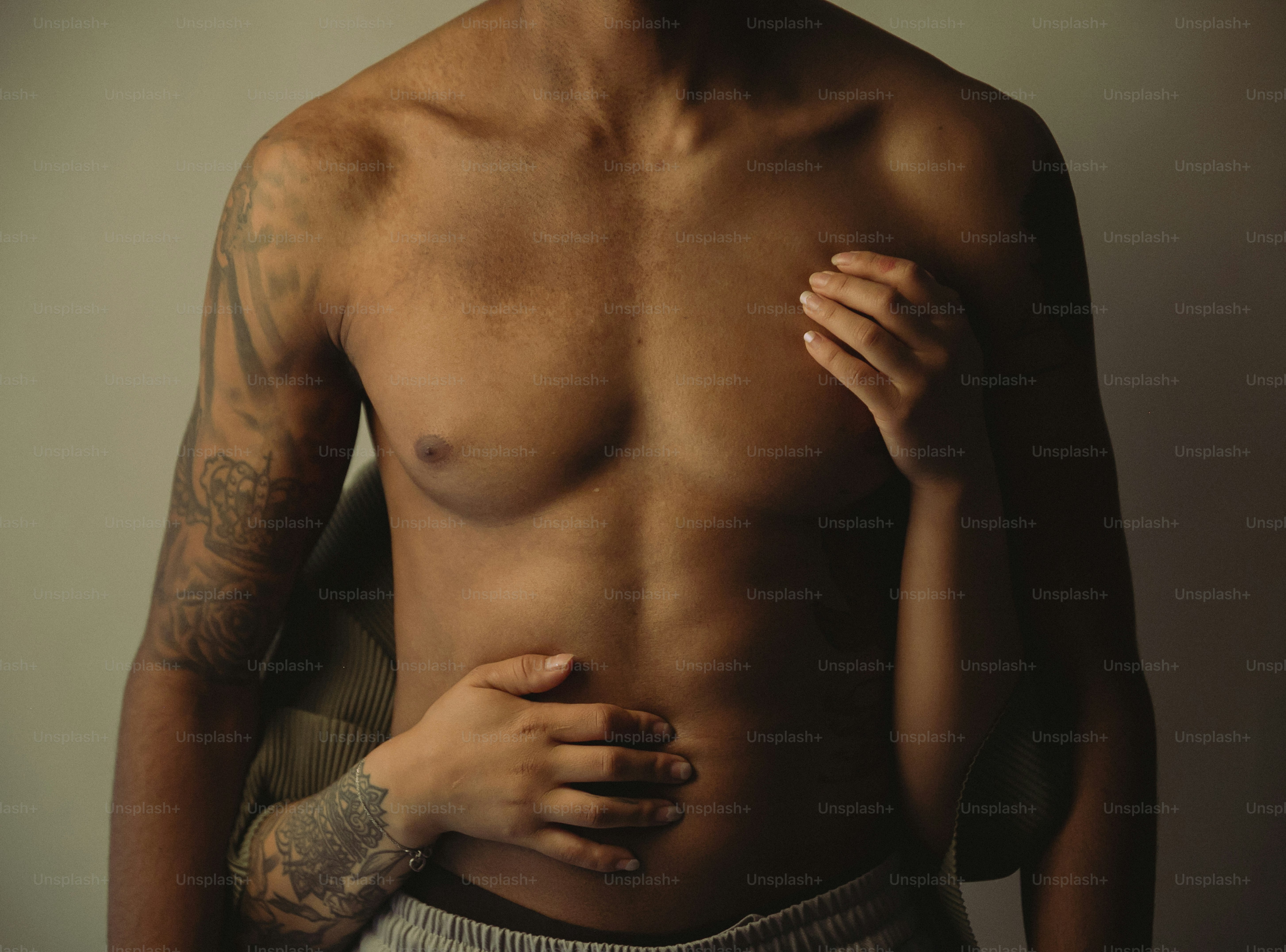 a man with a tattooed arm holding his chest