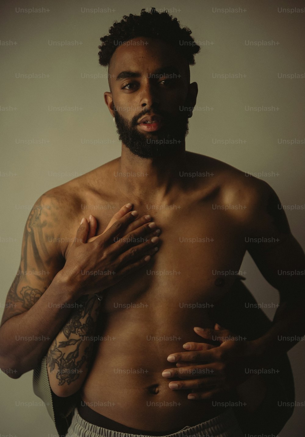 a man with a beard and no shirt holding his hands together