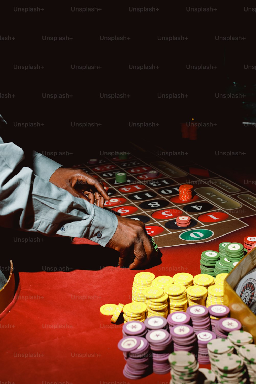 カジノのテーブルでチップの山の隣に座る男性
