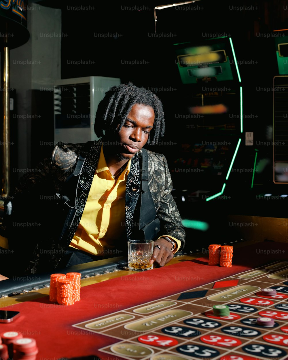 Ein Mann sitzt mit einem Glas Whiskey an einem Casinotisch