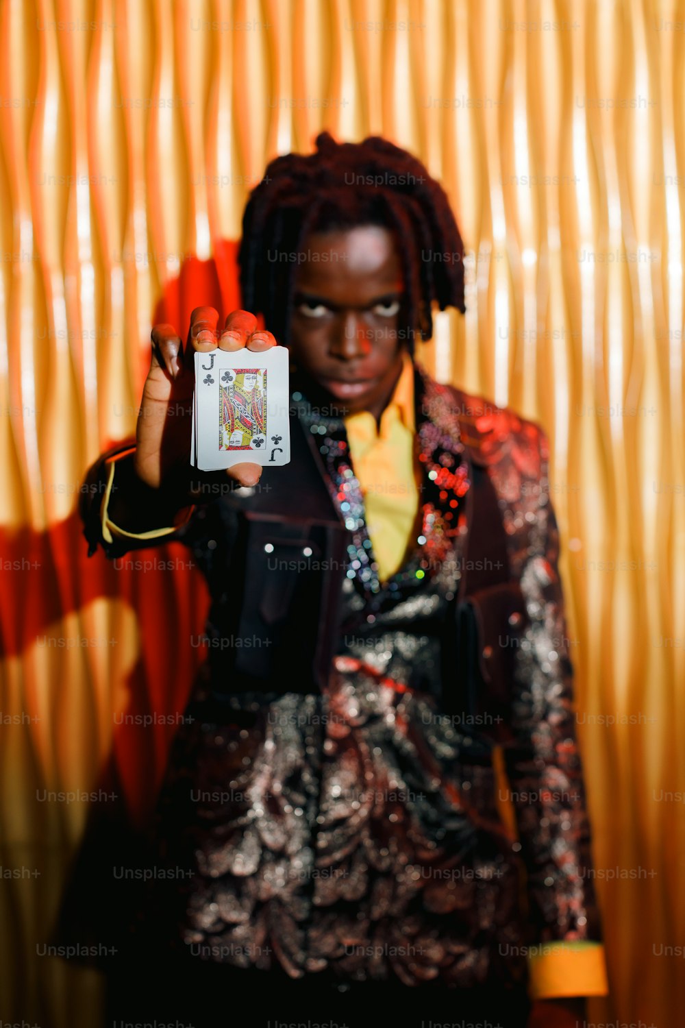 a man with dreadlocks holding up a playing card